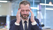 © stockbakers - The Portrait of Tired Businessman having Headache in Office