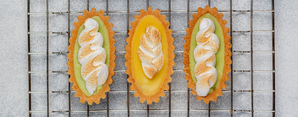 Wall Mural - Shortbread cake baskets dough with fruit puree (Apple, mango, peach, melon) and meringue. Delicious crunchy dessert for gourmets. Selective focus, top view, banner, long image
