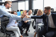 © ty - Happy young people sitting in office and giving high five to their colleagues.