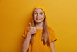 Portrait of freckled girl shows thumb up, agrees with something and says okay, like gesture, looks positively, wears yellow clothes in one tone with background. Children, body language concept