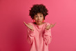 © WHstudio Leushin N - Photo of doubtful Afro American lady shrugs shoulders, makes decision, faces dilemma, feels apathy, hesitates as makes choice, looks questioned, isolated on pink background. People, attitude