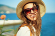© vitaliymateha - Closeup bright portrait joyful woman tourist in straw hat and sunglasses looking to camera wiht smile.