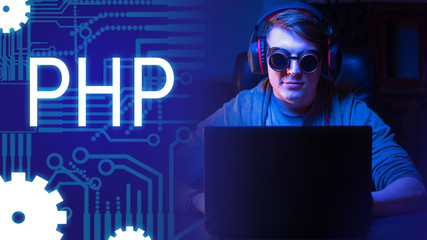 A man wearing headphones and round glasses sits at a computer on the background of the inscription PHP. Hypertext Preprocessor. Interpreted programming language. PHP scripting language.