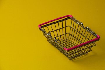 Wall Mural - Shopping basket on a yellow background. Supermarket food price concept.