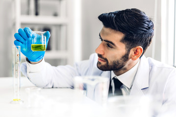 Professional scientist man research and working doing a chemical experiment while making analyzing and mixing  liquid in test tube.Young science man looking sample chemical on glass at laboratory