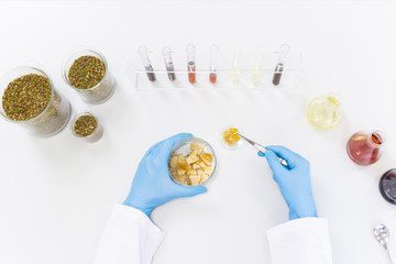 Hands working with terpene CBD crystals in laboratory with tweezers