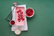 © The Picture Pantry - Pink ice cream with raspberries and red currants on green background. Top view