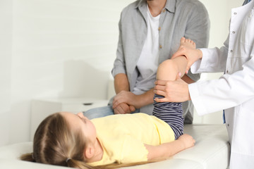 Canvas Print - Professional orthopedist examining little patient's leg in clinic