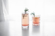 © The Picture Pantry - Pink grapefruit drink in two decorative glasses on a white background, garnished with rosemary.