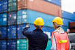 Warehouse shipping transportation concept. Commercial docks worker and inspector at commercial dock. Workers are wearing protective clothing they are standing against cargo containers.