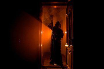 Silhouette of an unknown shadow figure on a door through a closed glass door. The silhouette of a human in front of a window at night. Scary scene halloween concept of blurred silhouette of maniac.