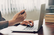 © tortoon - business man hand texting laptop and holding phone on wooden table