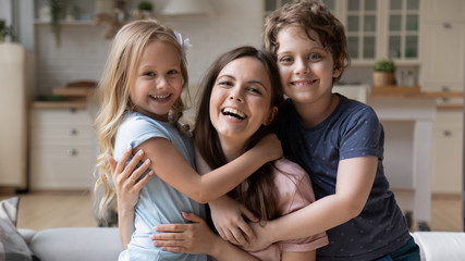 close up portrait of excited young mother and little preschooler children hug cuddle look at camera 