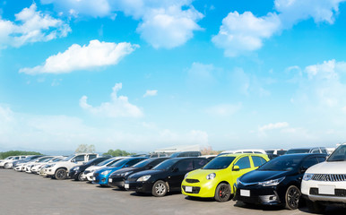 Wall Mural - Car parked in large asphalt parking lot with white cloud and blue sky background.