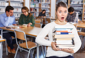 Wall Mural - Surprised girl sitting in library