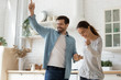 © fizkes - Happy loving couple dancing in modern kitchen together, smiling husband holding beautiful wife hand, moving to favorite popular music, celebrating relocation, mortgage or having fun on date