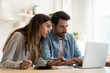 © fizkes - Focused young couple calculating bills, discussing planning budget together, serious wife and husband looking at laptop screen, using online banking services and calculator, checking finances