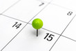 Green pinned pin in calendar on 15th day.