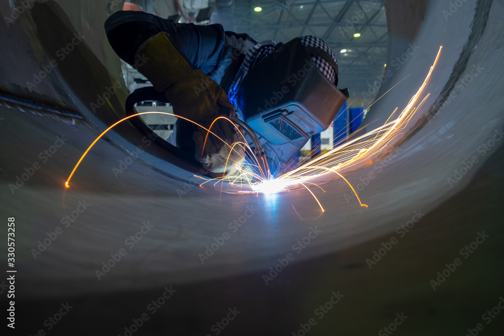 Welder performs welding work semi-automatic electric arc welding. Stainless steel pipe welding. Pipe production. - obrazy, fototapety, plakaty 