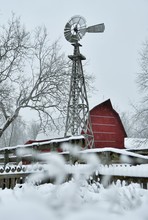 Winter, Snow Covered, Landscape Scene With A Windmill And Red Barn In The Background