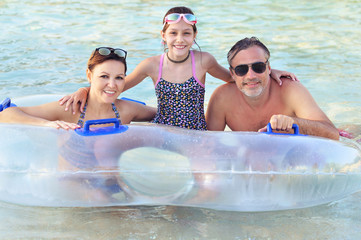 Wall Mural - Happy Dad, mother and daughter relax in the pool