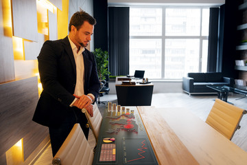 Wall Mural - Businessman looking at map of coronavirus pandemic and economy and financial markets collapse by corona virus outbreak and pandemic. Global economy hit and covid crisis infographic.