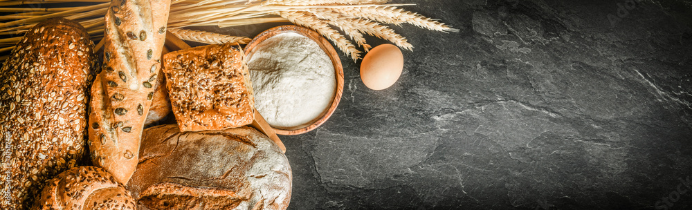 Bread with wheat and bowl of flour on dark board, White bakery food concept panorama or wide banner photo. - obrazy, fototapety, plakaty 