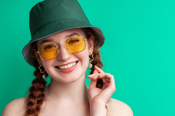 Happy smiling fashionable woman wearing yellow sunglasses, trendy green bucket hat. Close up portrait. Copy, empty space for text