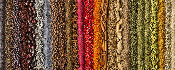 Spices scattered on the table, background for design. Colorful condiments as decoration of packing with food.