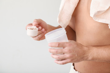 Poster - Sporty man with protein on light background, closeup