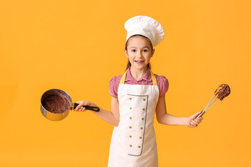 Poster - Little housewife with melted chocolate in saucepan and whisk on color background