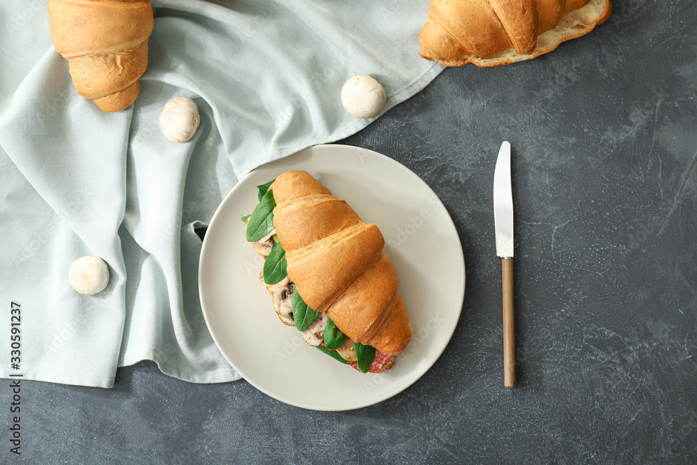 Tasty croissant sandwich on dark background