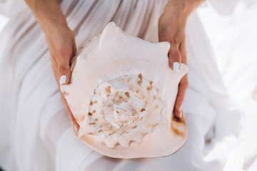 beautiful girl in a white dress and holds a large sea shell