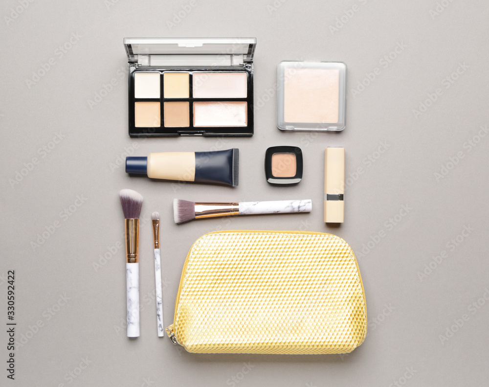 Bag with makeup brushes and decorative cosmetics on grey background