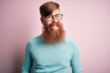 Poster - Handsome Irish redhead man with beard wearing glasses over pink isolated background winking looking at the camera with sexy expression, cheerful and happy face.