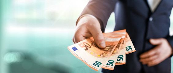 Business Man give a spread of euros cash over bank background. Euro currency detail. Money Banknotes wide banner.