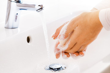 Wall Mural - Woman use soap and washing hands under the water tap. Hygiene concept hand detail.