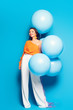 © LIGHTFIELD STUDIOS - full length view of cheerful stylish woman with big festive balloons smiling at camera on blue background
