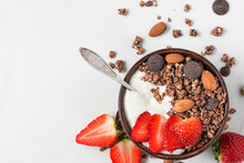 Bowl Of Oat Chocolate Granola With Yogurt, Fresh Strawberries And Nuts With A Spoon On White Marble Background