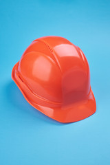 orange protective helmet and safety glasses near it on a bright blue background. protective workwear and construction industry concept.