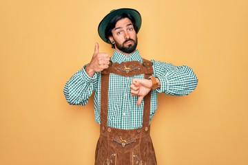 Wall Mural - Young handsome man wearing tratidional german octoberfest custome for Germany festival Doing thumbs up and down, disagreement and agreement expression. Crazy conflict