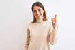 © Krakenimages.com - Beautiful redhead woman wearing winter turtleneck sweater over isolated background doing happy thumbs up gesture with hand. Approving expression looking at the camera showing success.