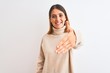 © Krakenimages.com - Beautiful redhead woman wearing winter turtleneck sweater over isolated background smiling friendly offering handshake as greeting and welcoming. Successful business.