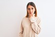 © Krakenimages.com - Beautiful redhead woman wearing winter turtleneck sweater over isolated background looking confident at the camera with smile with crossed arms and hand raised on chin. Thinking positive.