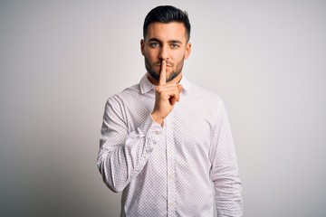 Canvas Print - Young handsome man wearing elegant shirt standing over isolated white background asking to be quiet with finger on lips. Silence and secret concept.