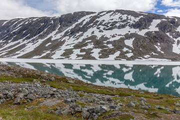 snow mountains surrounded by clouds in norwegian fiord reflection in water selective focus