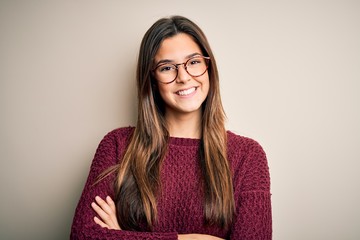 Young beautiful girl wearing casual sweater and glasses over isolated white background happy face smiling with crossed arms looking at the camera. Positive person.