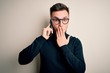 © Krakenimages.com - Young handsome caucasian man having a conversation talking on smartphone cover mouth with hand shocked with shame for mistake, expression of fear, scared in silence, secret concept