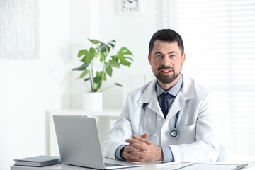 Wall Mural - Portrait of male doctor in white coat at workplace