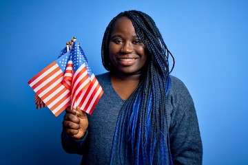 Sticker - Young patriotic african american plus size woman with braids holding united states flags with a happy face standing and smiling with a confident smile showing teeth